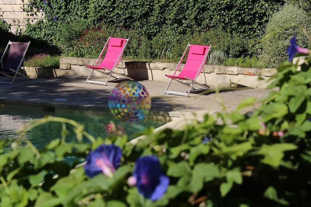 A pool area with pink lounge chairs and a colorful spherical object.