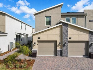 A modern two-story residential building with a garage, numbered 101 and 103, and a paved driveway.
