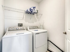 A laundry area with two front-loading washing machines and a drying rack above.