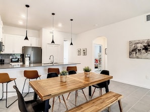 Cozinha moderna com ilha central, cadeiras pretas e iluminação pendente.