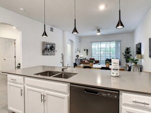 A modern kitchen with stainless steel appliances, white cabinetry, and pendant lighting. - Fairy Tale Disney Stay / Garage Access / Water Fun (Four Corners)