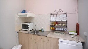 A compact kitchen with a microwave, toaster, and a shelf with dishes. - Apartment with Terrace (Yianna Cottage Studios) (Skopelos)