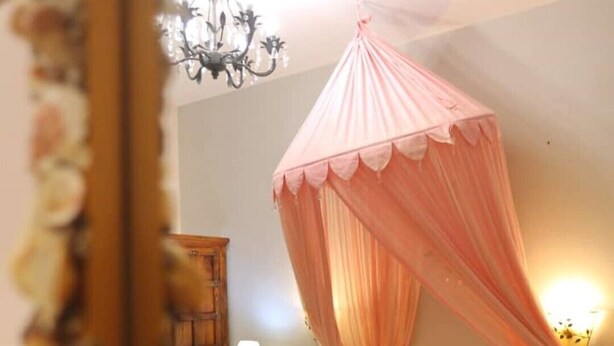A hotel room with a bed, a nightstand, a lamp, a chandelier, and a canopy bed. - Apartment with Terrace (Yianna Cottage Studios) (Skopelos)