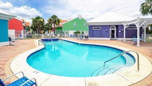 Ein Pool mit gewölbter Kante, umgeben von einer Ziegelterrasse und einem weißen Zaun.
