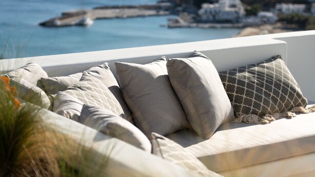 Un espace extérieur moderne, aménagé pour se détendre, avec vue sur la mer et sur une colline.