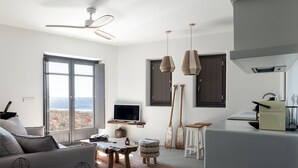 Un salon moderne avec un canapé, un téléviseur, une table basse en bois et de grandes fenêtres donnant sur un paysage magnifique.