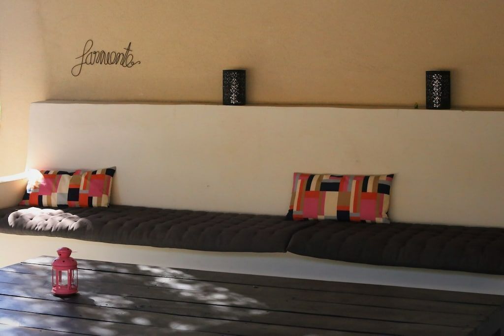 A cozy seating area with a cushioned bench, colorful pillows, and two wall-mounted speakers.