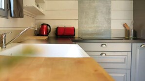 Une cuisine équipée d’un évier, d’une bouilloire et d’un sac rouge posé sur le plan de travail.