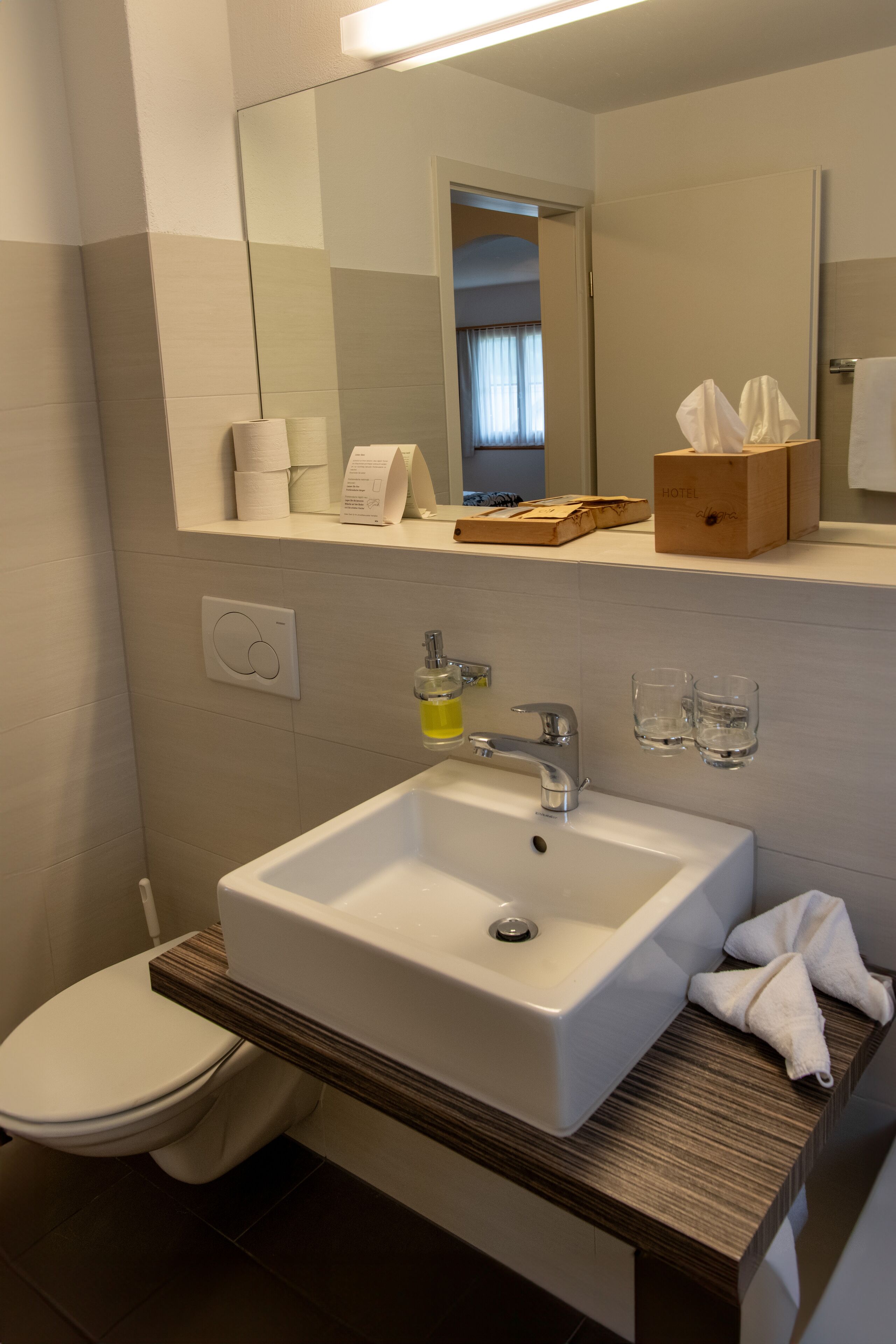 Un baño moderno con un lavamanos blanco, un espejo y un inodoro.