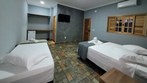 A room with two beds, a desk, a television, and a window with shutters. - Alto Costa Flats (Olímpia)