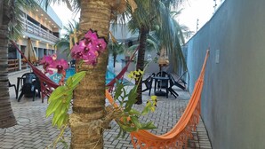 A courtyard with a hammock, chairs, and a pool area. - Alto Costa Flats (Olímpia)