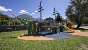 A playground with a slide, climbing structures, and a ship-themed design. - Porto Letizia Ferrara 3 (Porlezza)