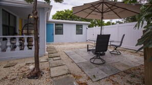 Eine Terrasse mit Tisch und Stühlen, eine blaue Tür und ein weißer Zaun.