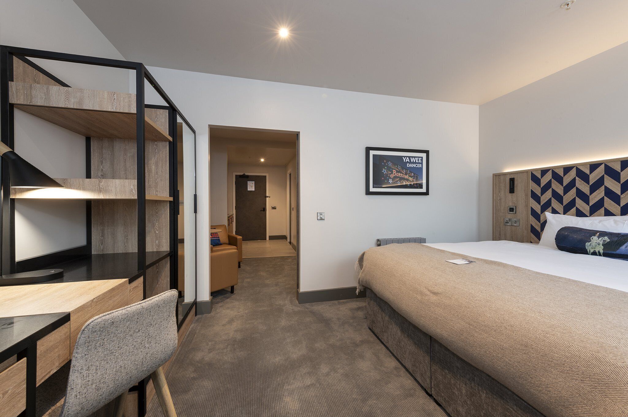 Una habitación de hotel moderna con una cama, un escritorio, una silla y una escalera.