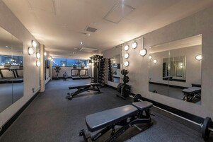 Un gimnasio con equipo de ejercicio, espejos y una cinta de correr.