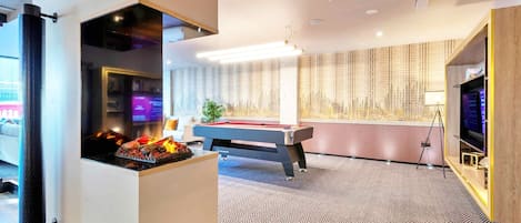 A modern indoor recreational area with a pool table, a fireplace, and a television.