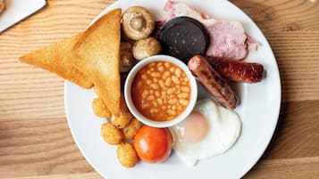 A plate of breakfast food including toast, beans, sausages, eggs, and mushrooms.