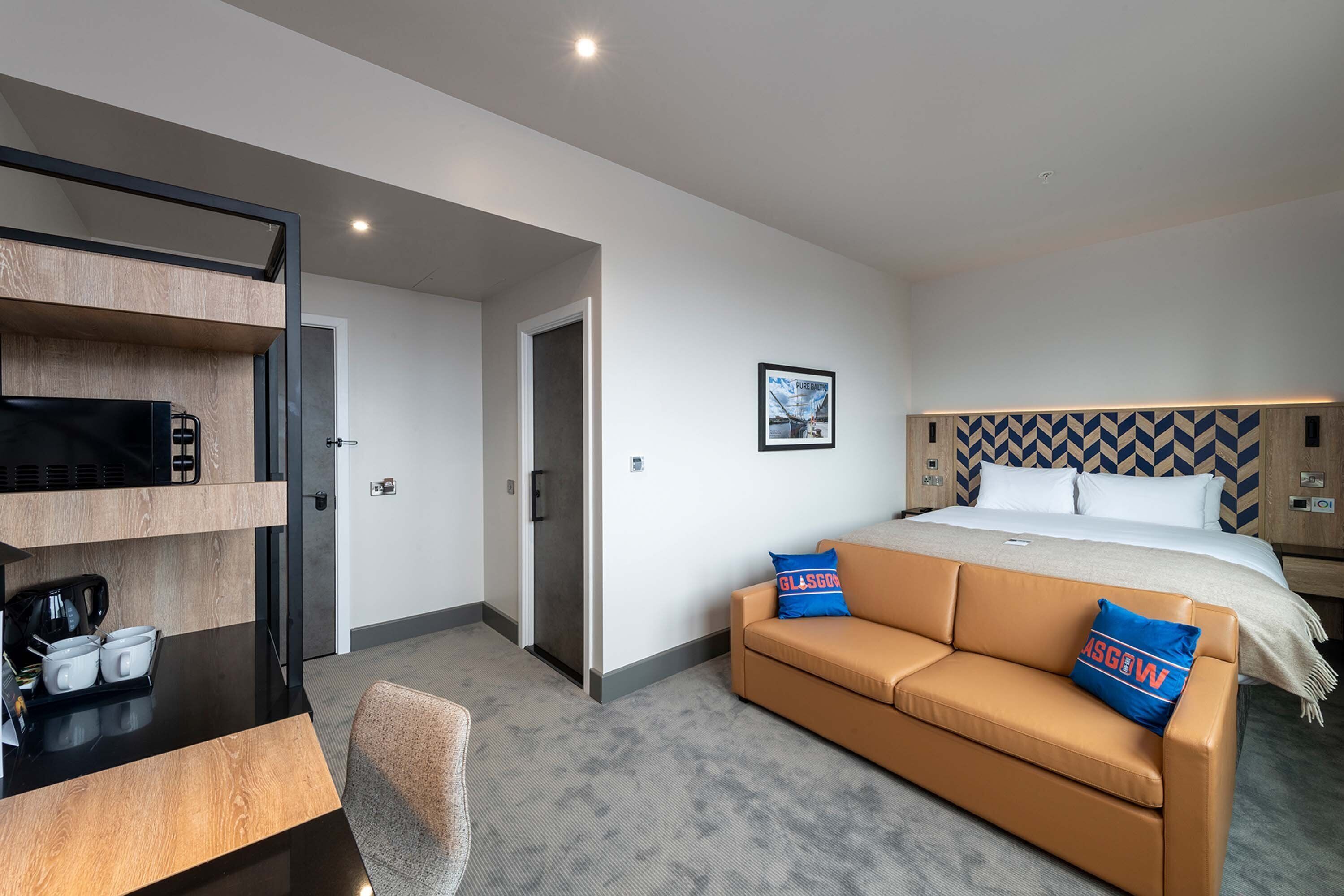 Een hotelkamer met een bed, een bank, een bureau met een koffiezetapparaat en een televisie.