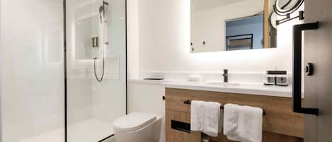Un bagno moderno con doccia vetrata, un WC bianco, un mobile lavabo in legno con specchio e un lavandino.