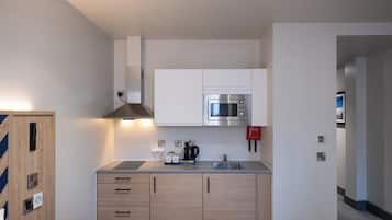 A modern kitchen with a built-in microwave, a coffee maker, and a sink.