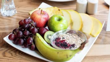 Un plato con frutas y un tazón de cereales sobre una mesa de madera.