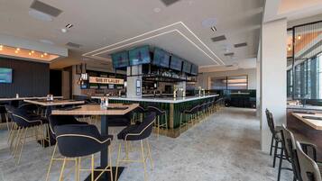 A modern bar area with multiple screens, a bar counter, and seating arrangements.