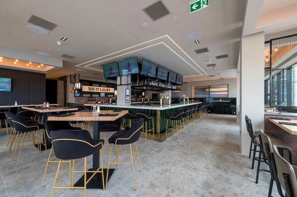 A modern bar area with multiple screens, a bar counter, and seating arrangements. - Sandman Signature Glasgow Hotel (Glasgow)