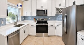 A modern kitchen with white cabinets, stainless steel appliances, and a tiled backsplash.