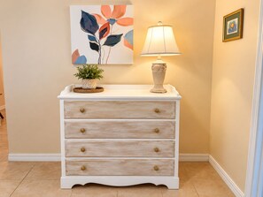 A white dresser with gold knobs, a potted plant, and a lamp on top. - Bikini Bungalow - King Beds and Short Walk to the Beach! Pet Friendly! (St. Augustine)