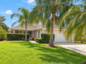 A residential house with a well-maintained lawn, palm trees, and a garage. - Bikini Bungalow - King Beds and Short Walk to the Beach! Pet Friendly! (St. Augustine)