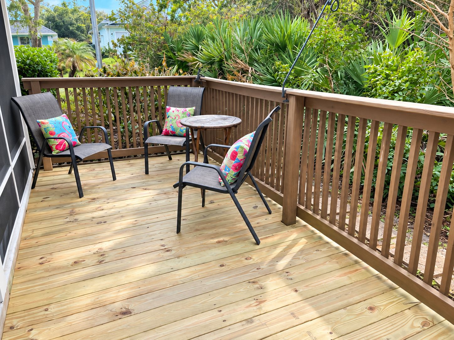 A wooden deck with two chairs and a small round table, surrounded by a wooden fence.