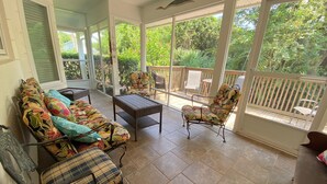 A covered patio with a sofa, chairs, and a table. - Bikini Bungalow - King Beds and Short Walk to the Beach! Pet Friendly! (St. Augustine)