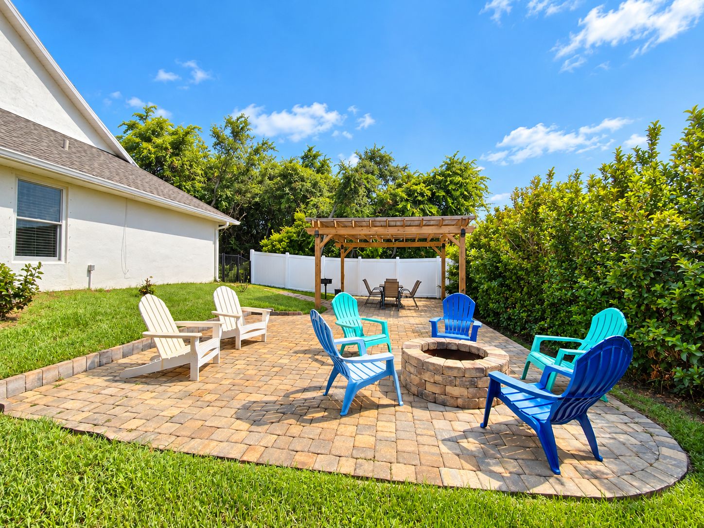 Une terrasse à l’arrière de la maison, avec un foyer extérieur, des sièges de jardin et une pergola.