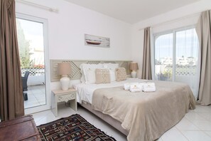 Quarto de hotel com cama, mesas de cabeceira, cortinas numa janela e vista para o exterior.