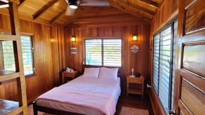 A wooden cabin bedroom with a bed, nightstands, and a window with blinds.