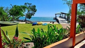A covered outdoor area with a view of the sea, a grassy lawn, and a gazebo.