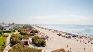 Ein Strand mit einem Weg, Strandzelten und einer Stadtkulisse im Hintergrund.