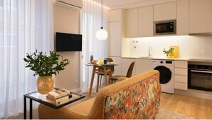 A modern living room with a sofa, a coffee table with a plant, a TV, and a dining area with a table and chairs. - Wanderlust Apartment, by Bolhão Residences (Porto)