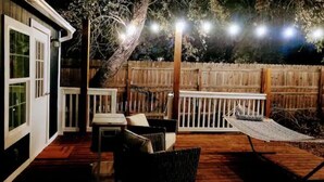 A wooden deck with a white railing, a hammock, and a table with chairs. - Golden oak one bedroom w a cool patio for vacation (Austin)