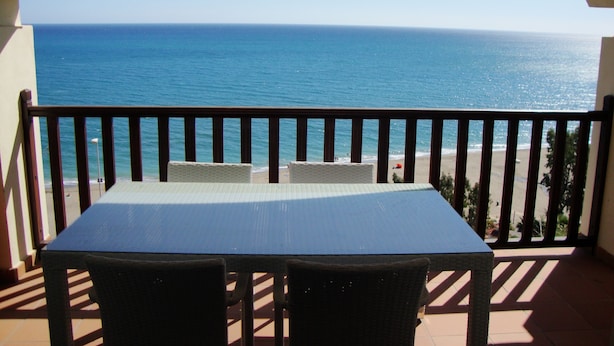 Varanda com mesa e cadeiras com vista para a praia.