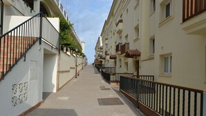 Uma rua estreita no centro da cidade, com prédios altos, varandas e uma calçada para pedestres.