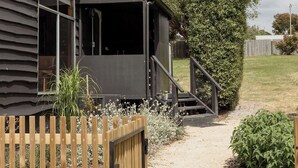 A modern house with a covered outdoor area, a wooden fence, and a gravel path leading to the house.