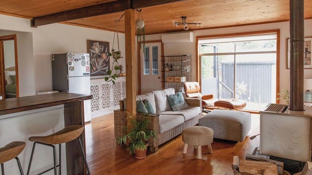 A cozy living area with a wooden ceiling, a kitchen with a refrigerator, a sofa, and a coffee table.