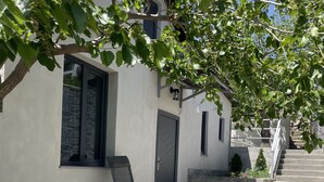 A modern building with a staircase leading to a second floor, a metal chair, and a tree providing shade. - House in Antarayin, Yerevan, Armenia (Yerevan)