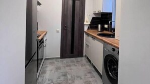 A compact kitchen with a washing machine, a dark wooden door, and a small countertop. - House in Antarayin, Yerevan, Armenia (Yerevan)