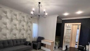 A modern living room with a grey sofa, a dining table with chairs, a chandelier, and a patterned wall. - House in Antarayin, Yerevan, Armenia (Yerevan)