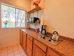 Enjoy cooking in this kitchen with a granite countertop and wooden cabinets, featuring a window with a view of the surrounding trees.
