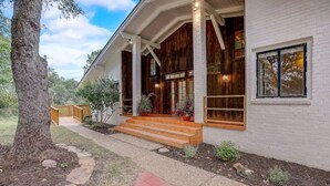A house with a covered porch, wooden steps, and a brick exterior.