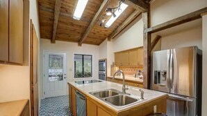 A kitchen with wooden cabinets, a stainless steel refrigerator, and a tiled floor.