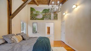 A bedroom with a large bed, a chandelier, and a painting on the wall.